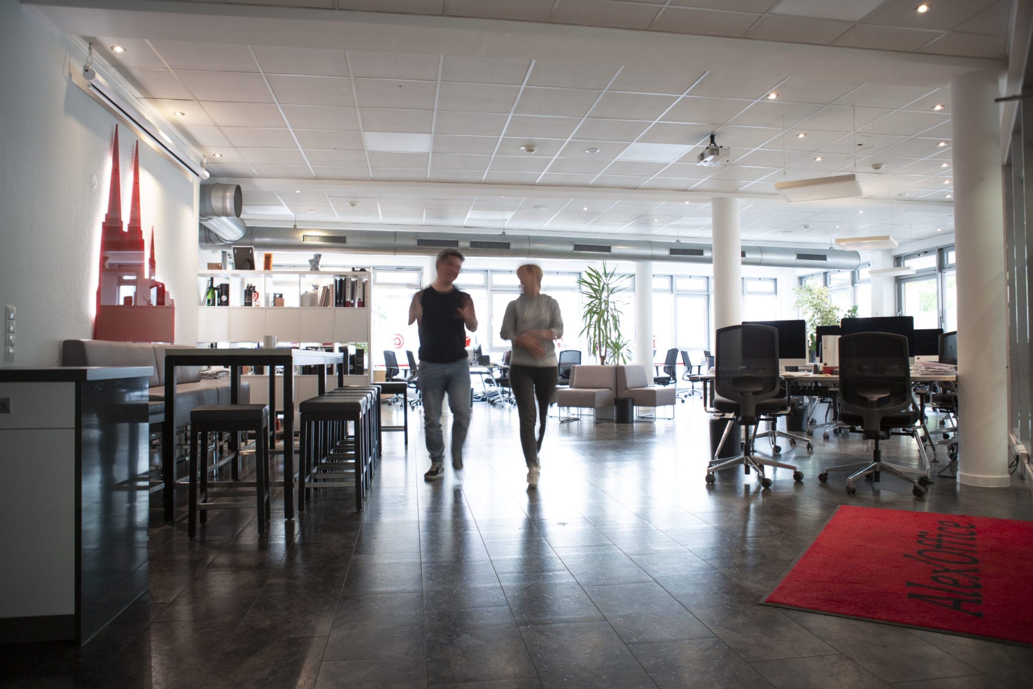 Zwei Menschen in einem Büro, die sich beim Gehen unterhalten Zwei Menschen in einem Büro, die sich beim Gehen unterhalten