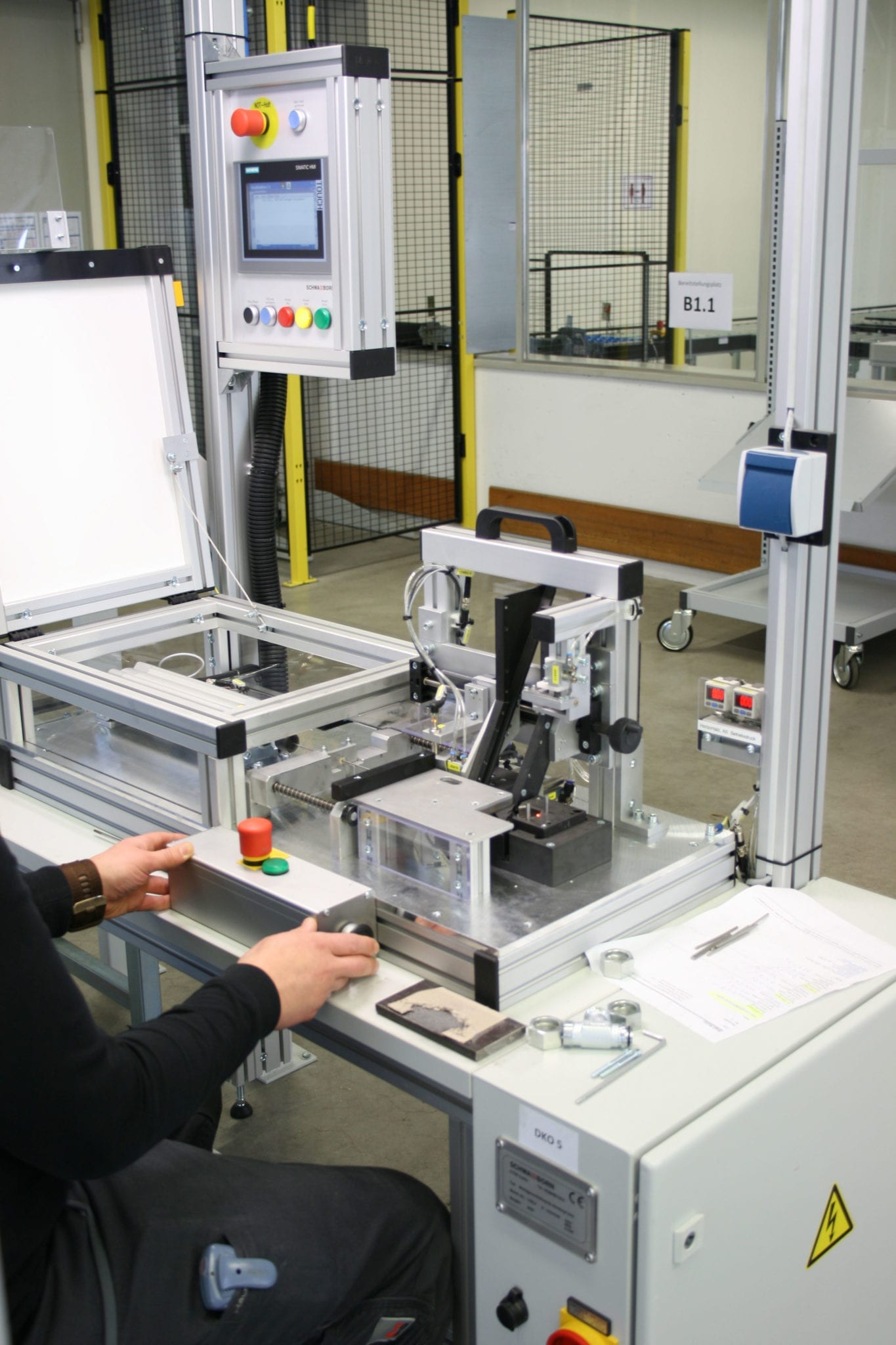Industrie- und Elektromontage in der Werkstatt in Köln-Porz Eine Person, die eine Maschine bedient